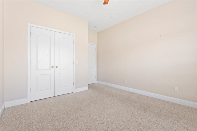 unfurnished bedroom featuring light carpet, baseboards, a closet, and a ceiling fan