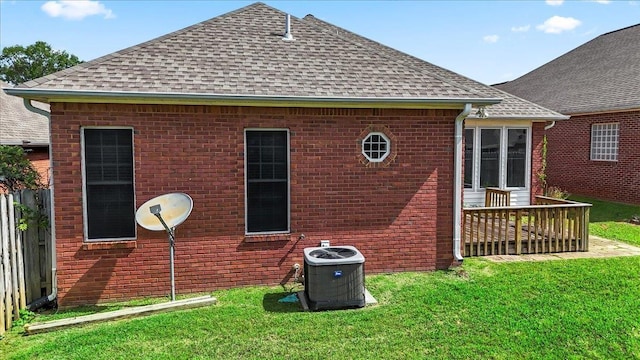 back of house featuring roof with shingles, central AC, and a yard