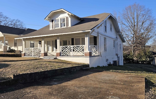 view of front of house with a front yard, cooling unit, and a porch