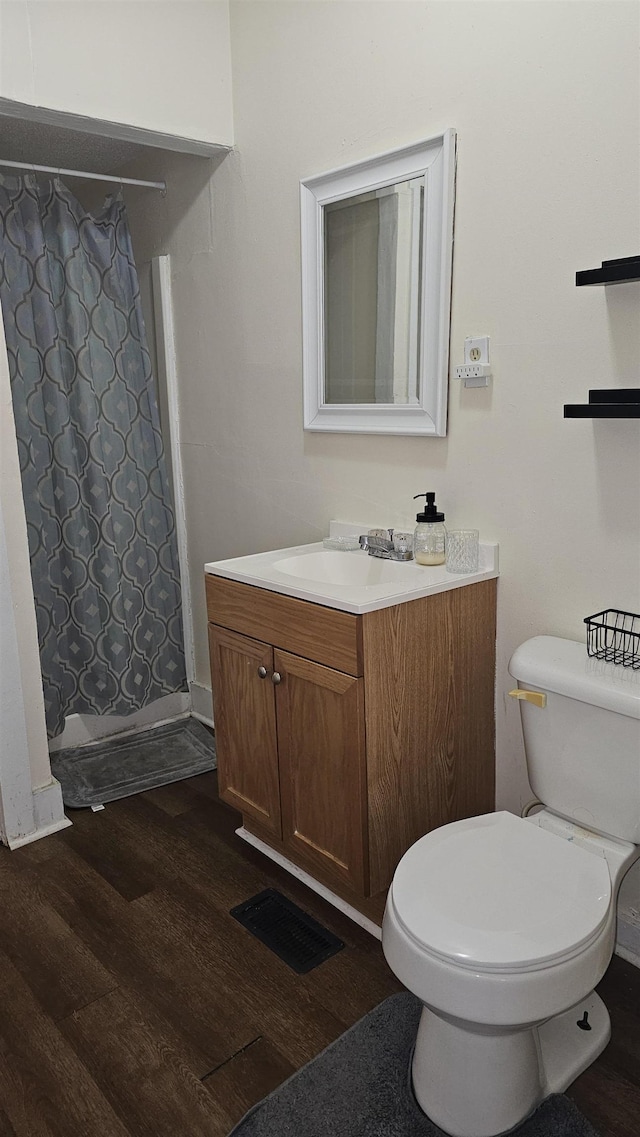 bathroom with toilet, walk in shower, hardwood / wood-style floors, and vanity