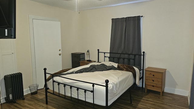 bedroom featuring a textured ceiling, dark hardwood / wood-style floors, and radiator heating unit