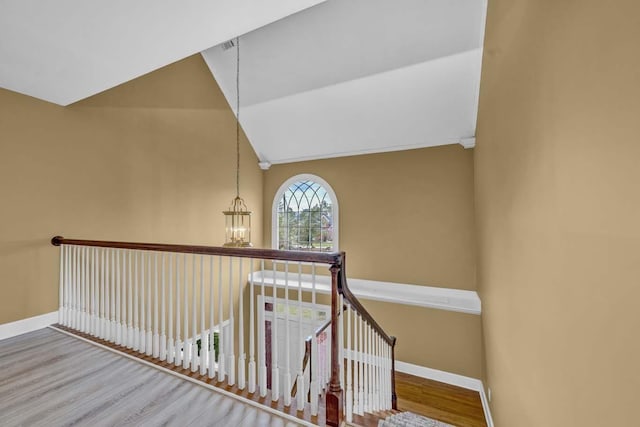 stairway with hardwood / wood-style floors, lofted ceiling, and a chandelier