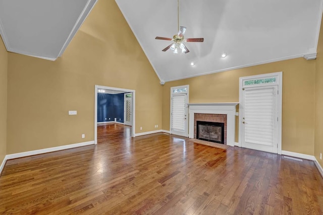 unfurnished living room with hardwood / wood-style floors, high vaulted ceiling, crown molding, a brick fireplace, and ceiling fan