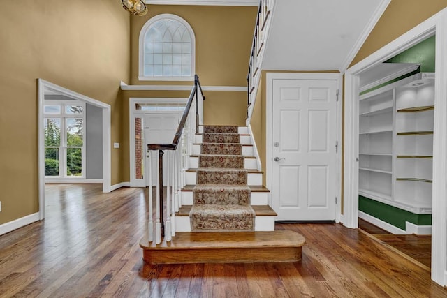 stairway featuring a high ceiling, hardwood / wood-style flooring, and ornamental molding