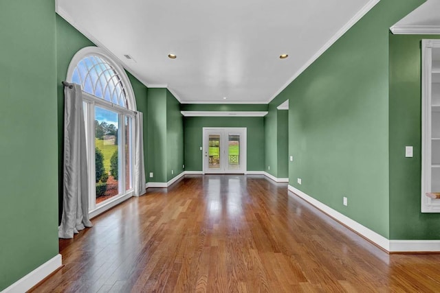 empty room with hardwood / wood-style floors, crown molding, and a healthy amount of sunlight