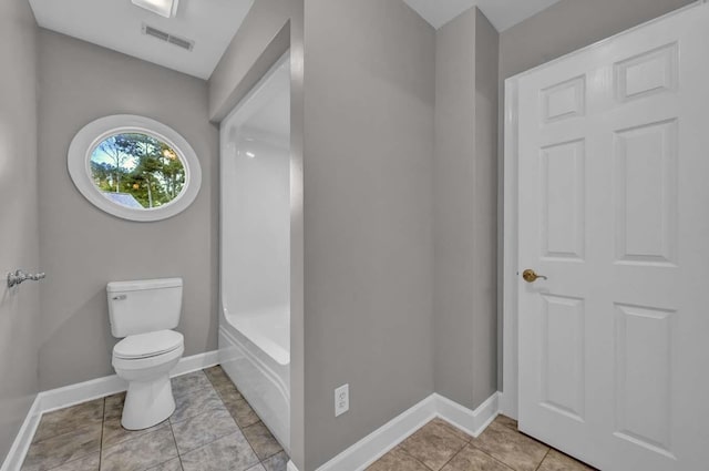 bathroom featuring tile patterned floors, a tub to relax in, and toilet