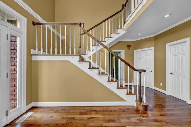 stairway with hardwood / wood-style flooring and crown molding