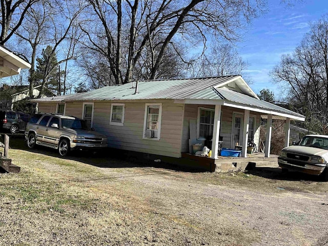 view of front facade with covered porch, metal roof, and driveway