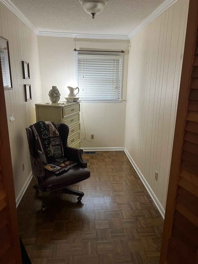 living area with a textured ceiling, dark parquet floors, crown molding, and wooden walls