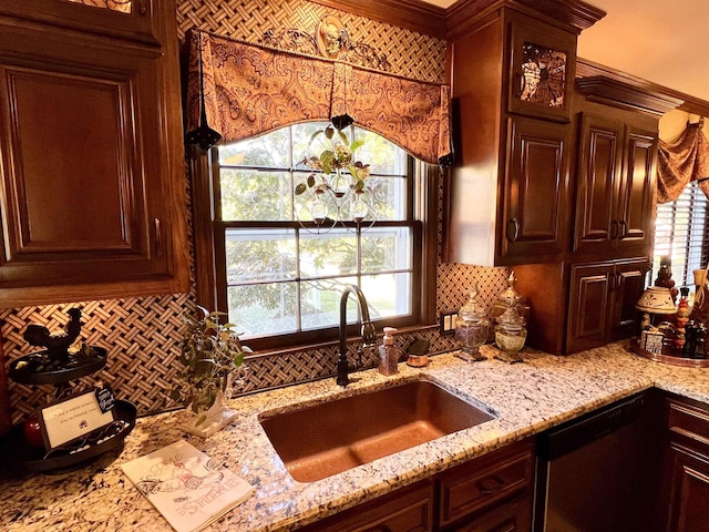 kitchen with dark brown cabinetry, light stone countertops, sink, and stainless steel dishwasher