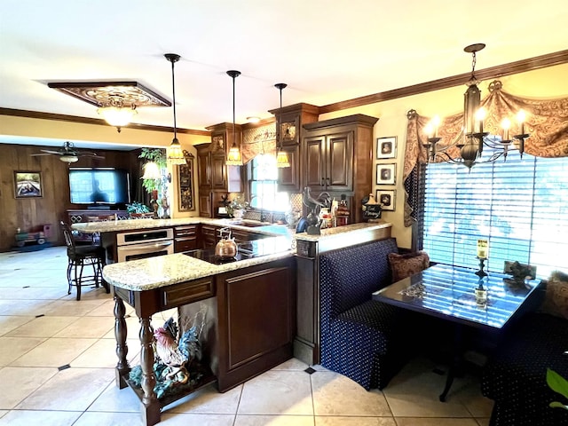 kitchen featuring oven, kitchen peninsula, hanging light fixtures, and ornamental molding