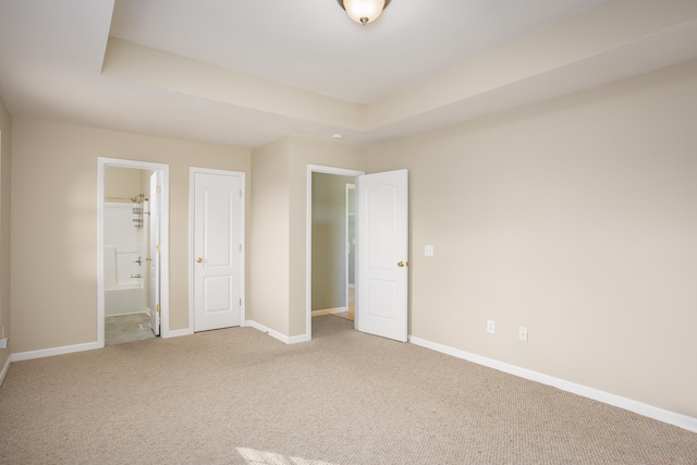 unfurnished bedroom with carpet, connected bathroom, and a raised ceiling