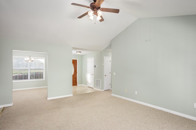 carpeted spare room with ceiling fan with notable chandelier and lofted ceiling