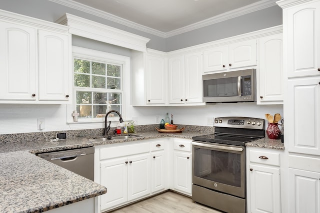 kitchen featuring appliances with stainless steel finishes, white cabinetry, a sink, and ornamental molding