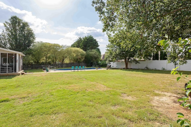 view of yard with a fenced in pool, a sunroom, and a fenced backyard