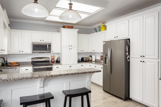 kitchen featuring appliances with stainless steel finishes, white cabinets, a sink, and ornamental molding