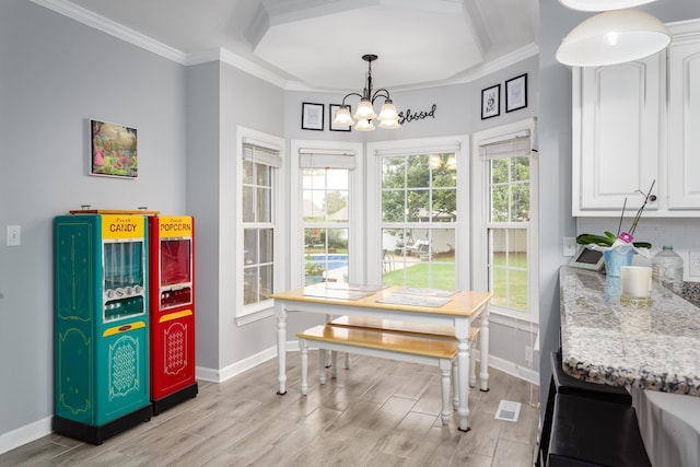 dining room with a chandelier, light wood-type flooring, crown molding, and baseboards