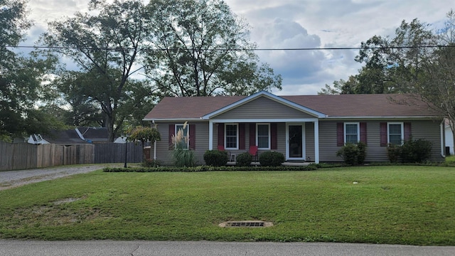 single story home with gravel driveway, fence, and a front lawn