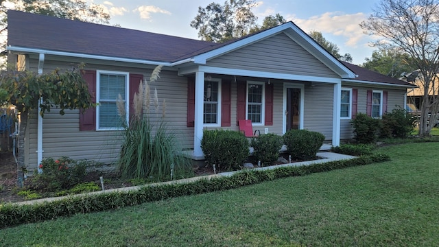 view of front of home with a shingled roof, a porch, and a front lawn