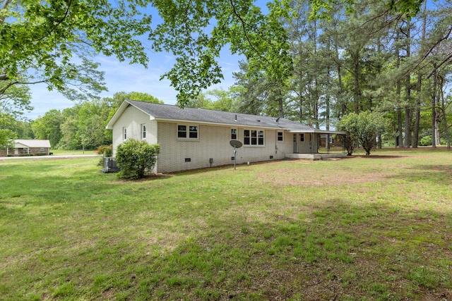 rear view of property featuring a yard, crawl space, cooling unit, and brick siding