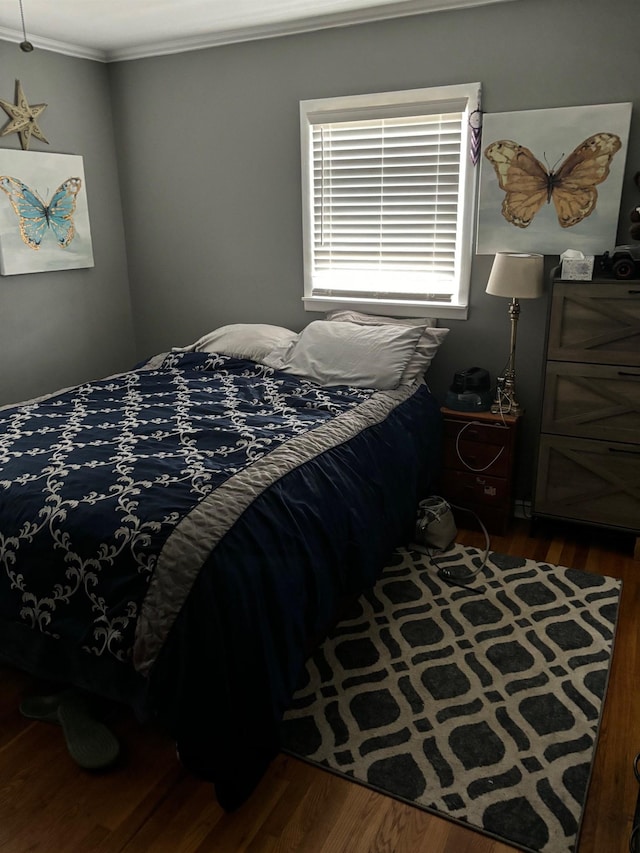 bedroom with ornamental molding and dark wood-type flooring