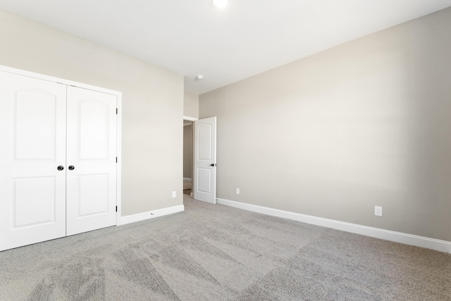 unfurnished bedroom with light colored carpet and a closet