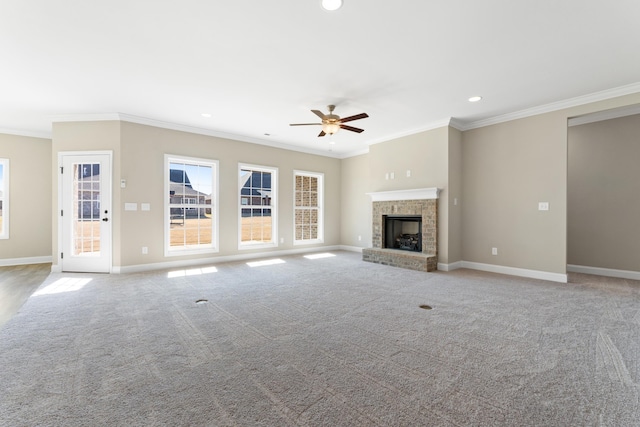 unfurnished living room featuring a brick fireplace, crown molding, light colored carpet, and ceiling fan