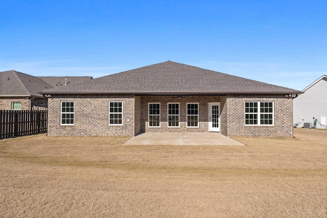 rear view of house with central AC, a patio area, and a lawn