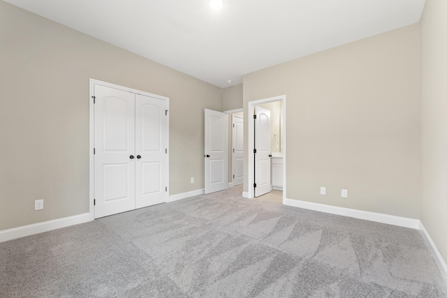 unfurnished bedroom featuring a closet, ensuite bathroom, and light carpet