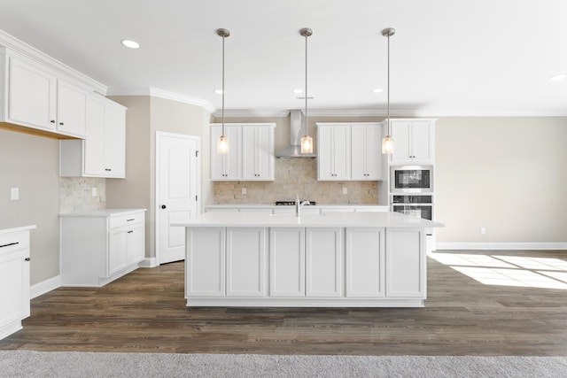 kitchen featuring white cabinetry, pendant lighting, a center island with sink, and wall chimney exhaust hood