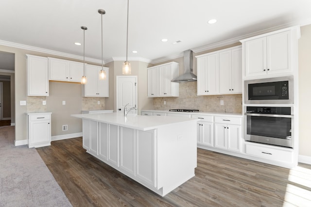 kitchen with stainless steel appliances, wall chimney range hood, dark hardwood / wood-style flooring, a center island with sink, and white cabinets