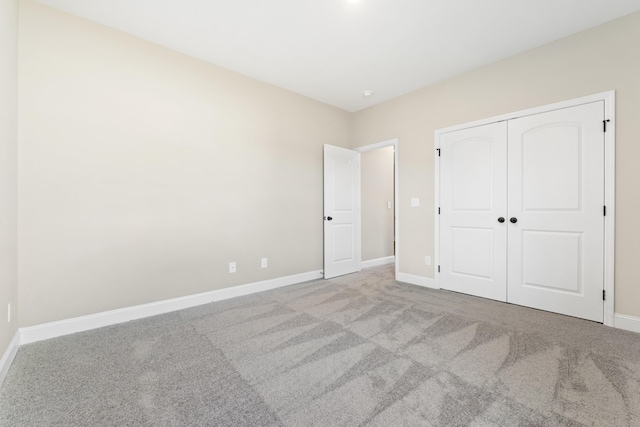 unfurnished bedroom featuring light carpet and a closet