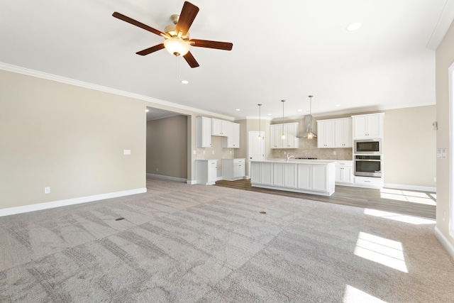 unfurnished living room featuring light colored carpet, ornamental molding, and ceiling fan