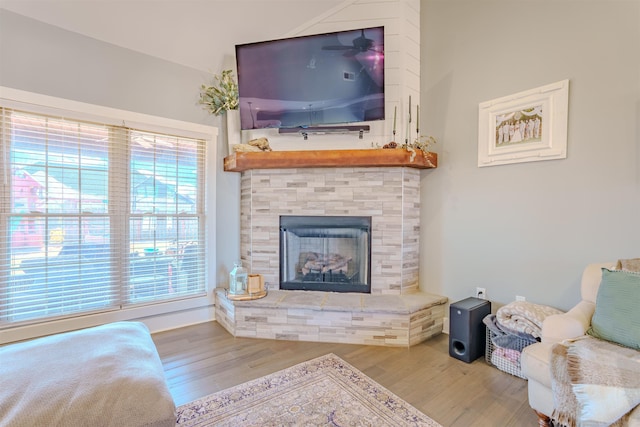 living room with light wood-style floors and a stone fireplace