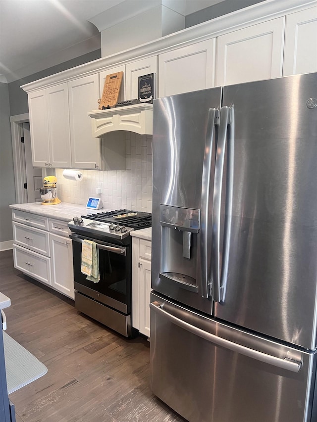 kitchen with light stone counters, stainless steel appliances, dark wood-type flooring, white cabinets, and tasteful backsplash