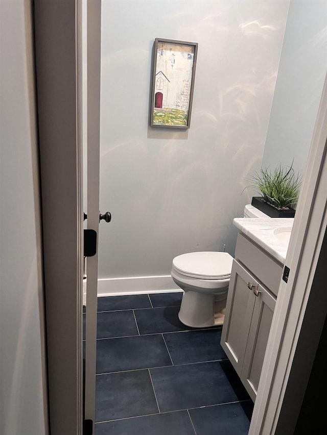 half bathroom with vanity, tile patterned flooring, toilet, and baseboards