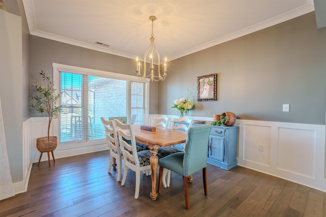 dining room with a notable chandelier, a wainscoted wall, dark wood-type flooring, visible vents, and crown molding