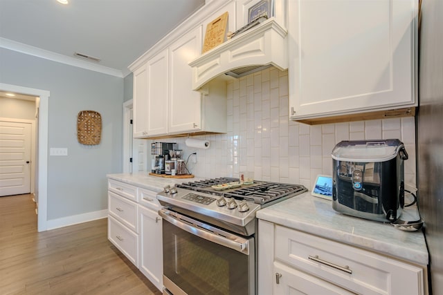 kitchen featuring white cabinets, stainless steel gas stove, visible vents, and custom exhaust hood