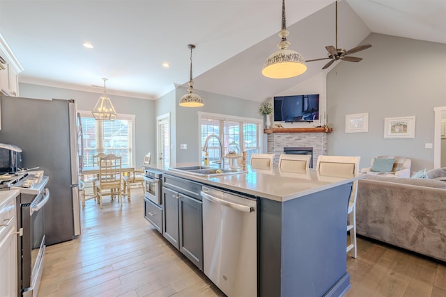 kitchen featuring light countertops, appliances with stainless steel finishes, open floor plan, a kitchen island with sink, and white cabinets