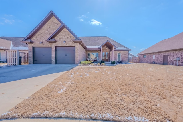 view of front facade with an attached garage, fence, concrete driveway, and brick siding