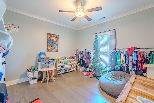 rec room featuring baseboards, visible vents, ceiling fan, wood finished floors, and crown molding