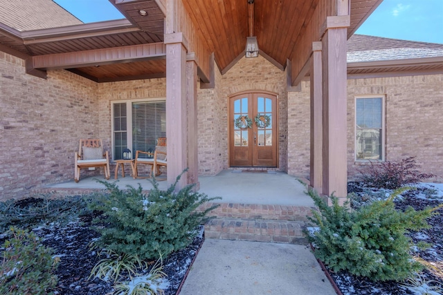 entrance to property featuring brick siding, roof with shingles, and french doors