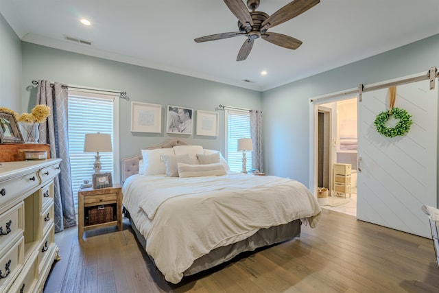 bedroom featuring light wood-type flooring, a barn door, multiple windows, and visible vents