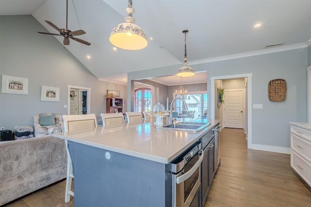 kitchen with a center island with sink, a breakfast bar, open floor plan, white cabinetry, and a sink