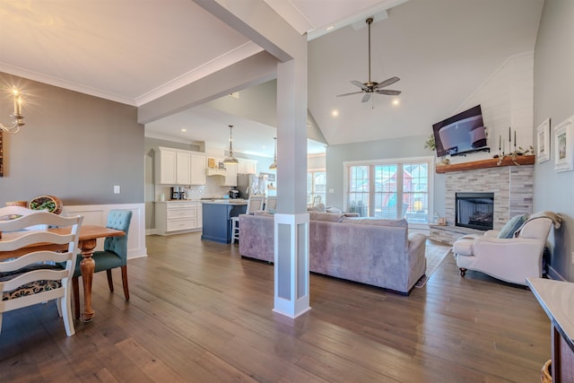 living area with high vaulted ceiling, a fireplace, dark wood finished floors, and ceiling fan