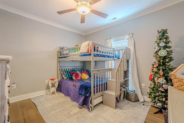 bedroom with ornamental molding, baseboards, visible vents, and light wood finished floors