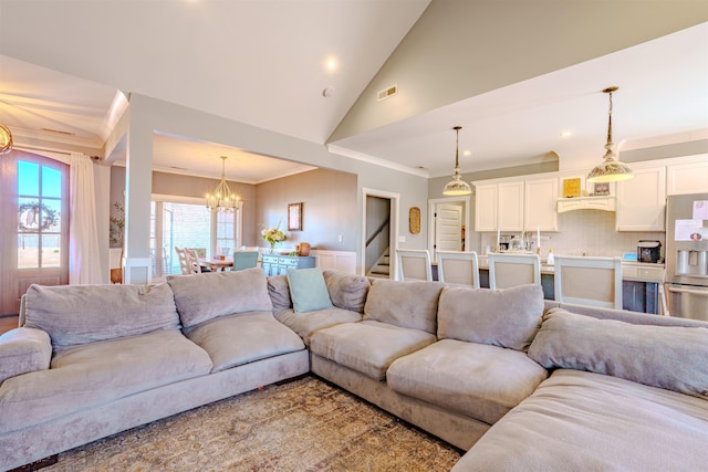 living area with crown molding, visible vents, an inviting chandelier, high vaulted ceiling, and stairs