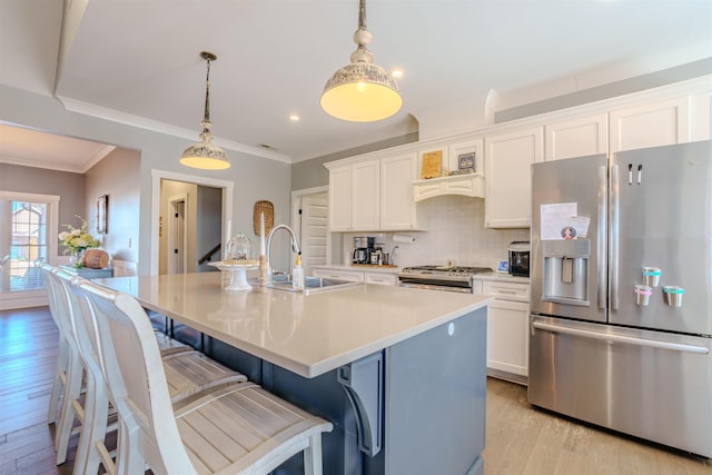 kitchen featuring decorative light fixtures, stainless steel appliances, a sink, light countertops, and a center island with sink