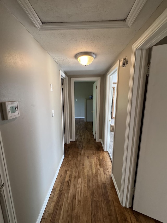  - corridor with wood finished floors, baseboards, and a textured ceiling