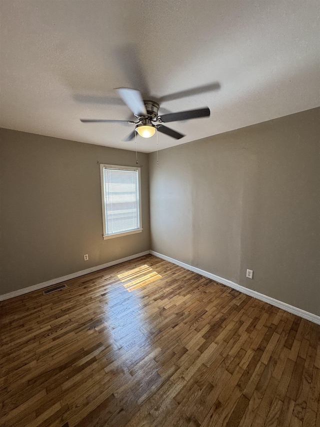  - empty room featuring wood finished floors, ceiling fan, and baseboards
